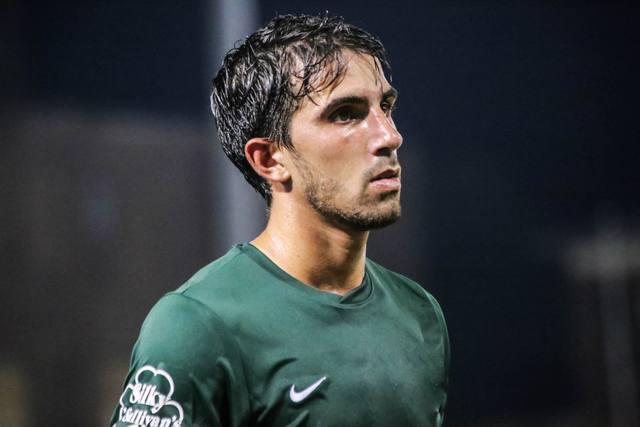Luca in a green kit under the lights at night.