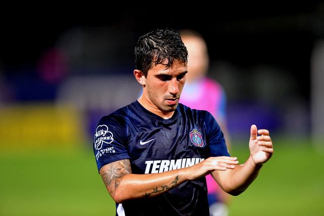 Luca in a navy kit adjusting his wrist tape.